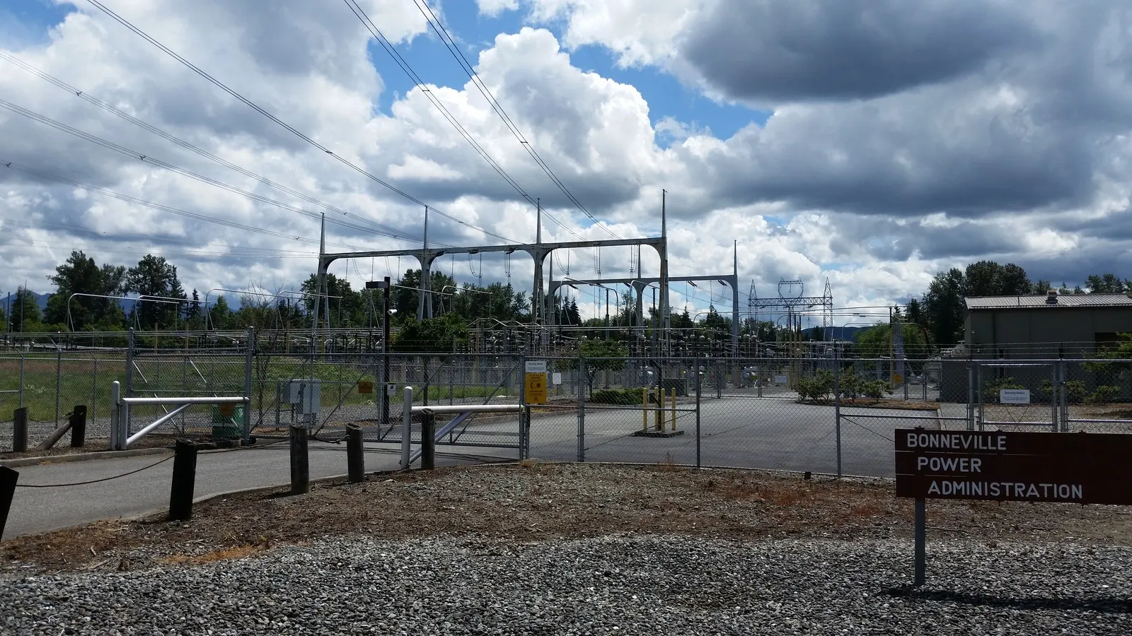 Outdoor Bonneville Power Administration 500 kV electrical substation with high-voltage structures, transmission lines, and a gravel foreground under a cloudy sky.